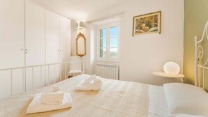 Ein Schlafzimmer mit Bett, Fenster, Heizkörper und einem Bild an der Wand.