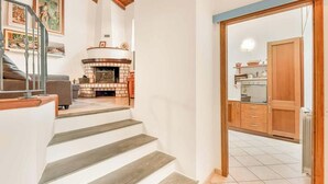 Eine Treppe führt zu einem Wohnzimmer mit Kamin, einer Küche mit Holdekor und einem Essbereich.