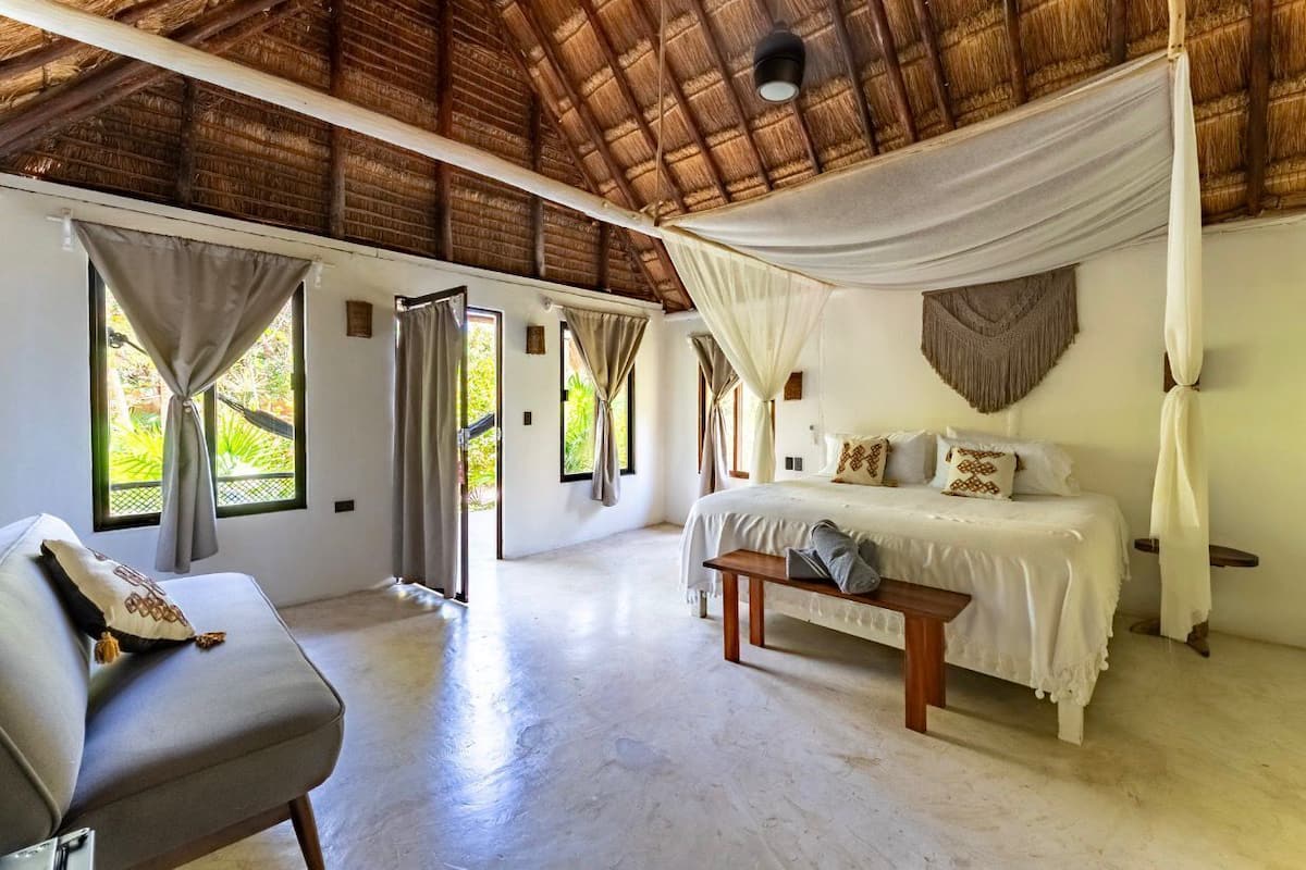 Une chambre à coucher avec un lit, un banc, un canapé et un baldaquin.