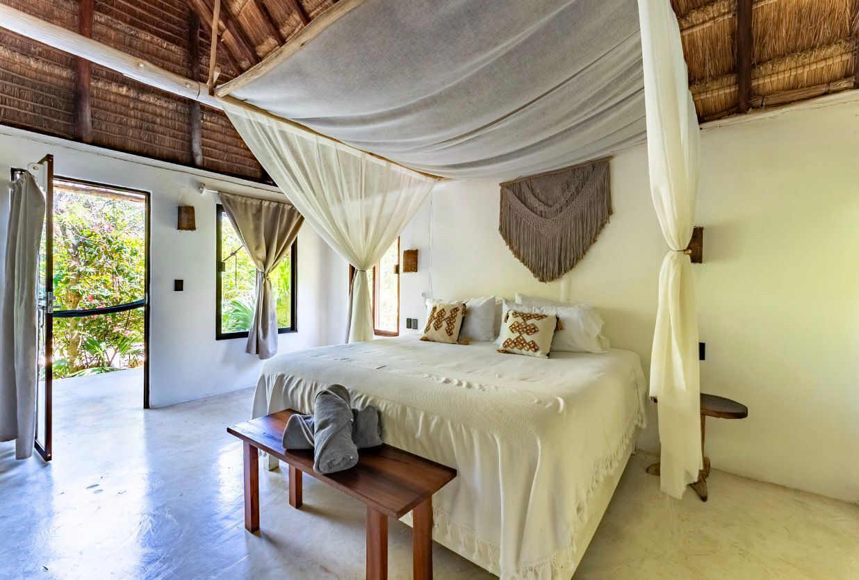 Un dormitorio con cama, banco y dosel.