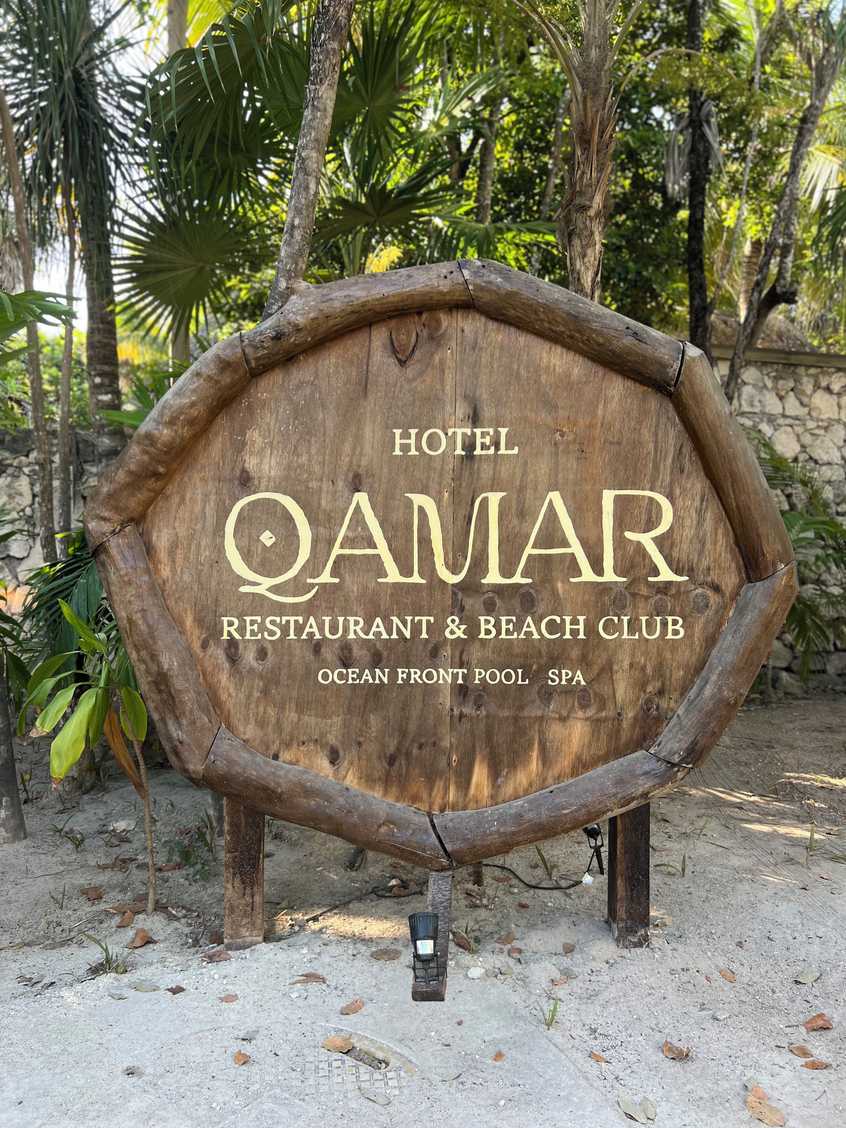 A wooden sign for Hotel Qamar, Restaurant & Beach Club, Ocean Front Pool SPA.