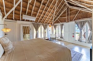 Un dormitorio amplio con una cama grande, una silla y un armario.