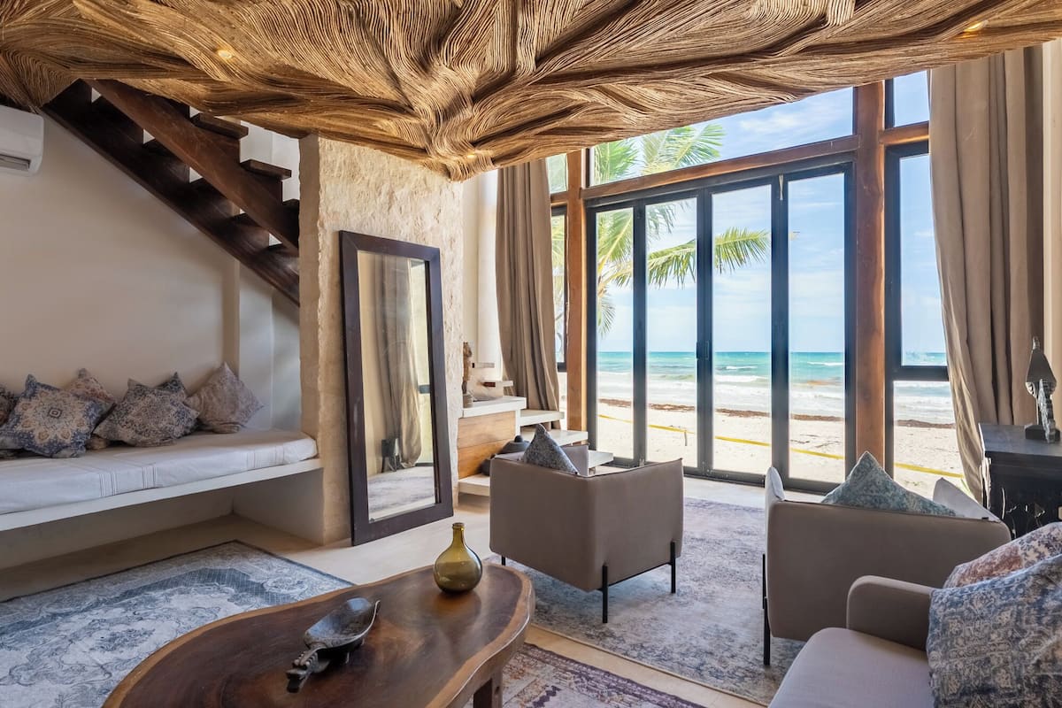 Une pièce avec un escalier, un canapé, une table basse et une vue sur la plage.