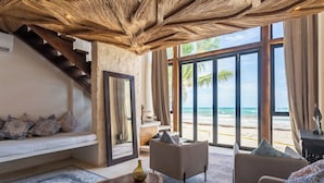 A room with a staircase, a sofa, a coffee table, and a view of the beach. - Hotel Qamar Lux (Tulum)