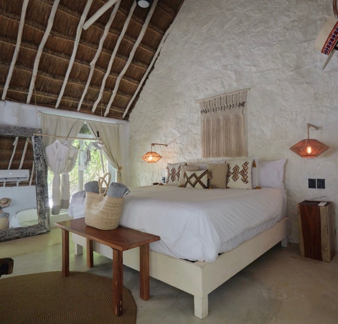 Une chambre à coucher avec un lit, des tables de chevet, un miroir et une fenêtre.