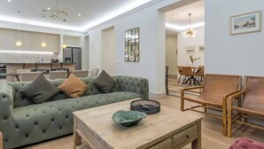 A modern living room with a green sofa, wooden coffee table, and a dining area with a wooden table and chairs. - Peaceful 4-bedroom apartment in charming Madrid perfect for families (Madrid)