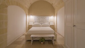 Une chambre à coucher avec un lit, un banc, une plante en pot et une porte.