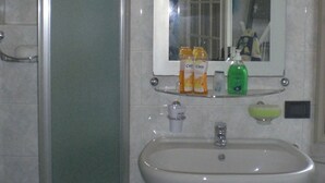 A bathroom with a white sink, a mirror, and toiletries on the countertop. - Charming marine living room accommodation in San Remo (Sanremo)
