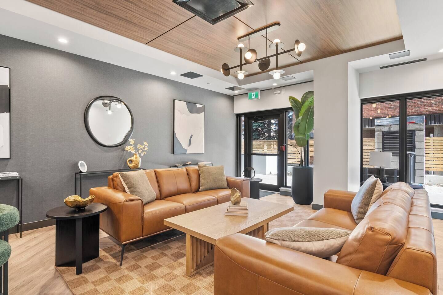 A modern lobby with leather sofas, a wooden coffee table, and a large mirror.