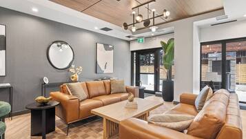 A modern lobby with leather sofas, a wooden coffee table, and a large mirror.