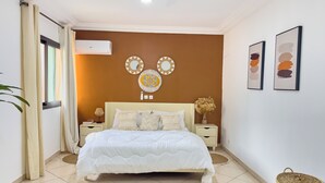 Ein Schlafzimmer mit Bett, Nachttischen, einer Wand-Klimaanlage und Wanddekoration.