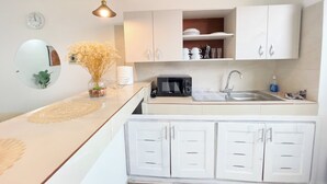 Una cocina moderna con armarios blancos, un microondas, un fregadero y un florero con flores secas.