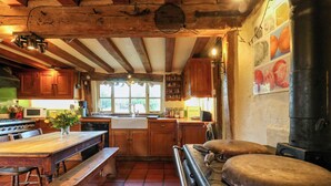 Una cucina rustica con travi in legno, un grande stufa e una panca di legno.