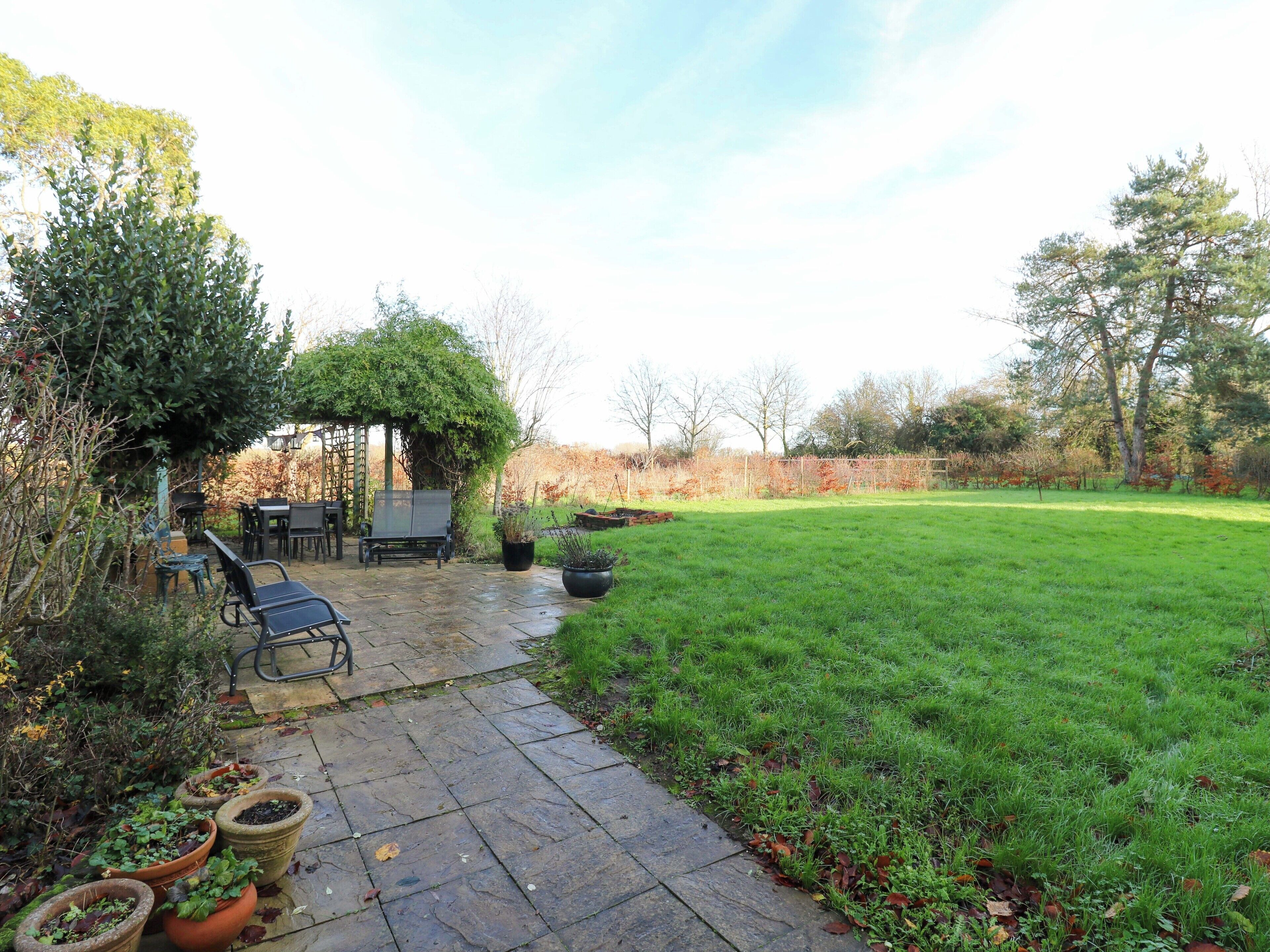 A patio area with a stone floor, outdoor furniture, and a grassy lawn.