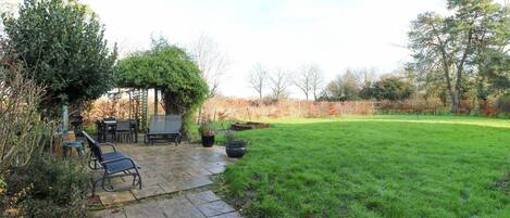A patio area with a stone floor, outdoor furniture, and a grassy lawn.