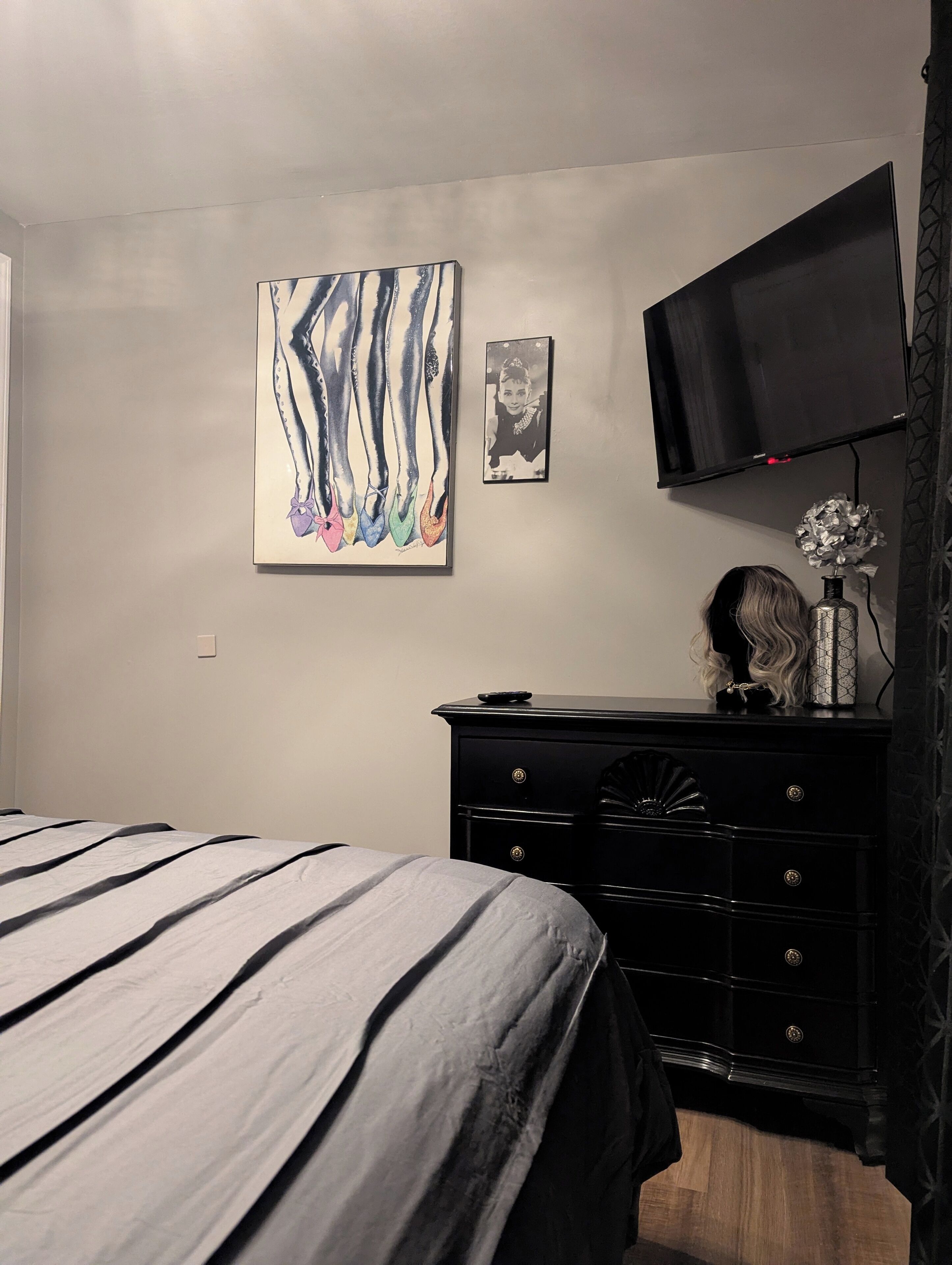 A bedroom with a bed, a dresser, a flat-screen TV, and wall art.