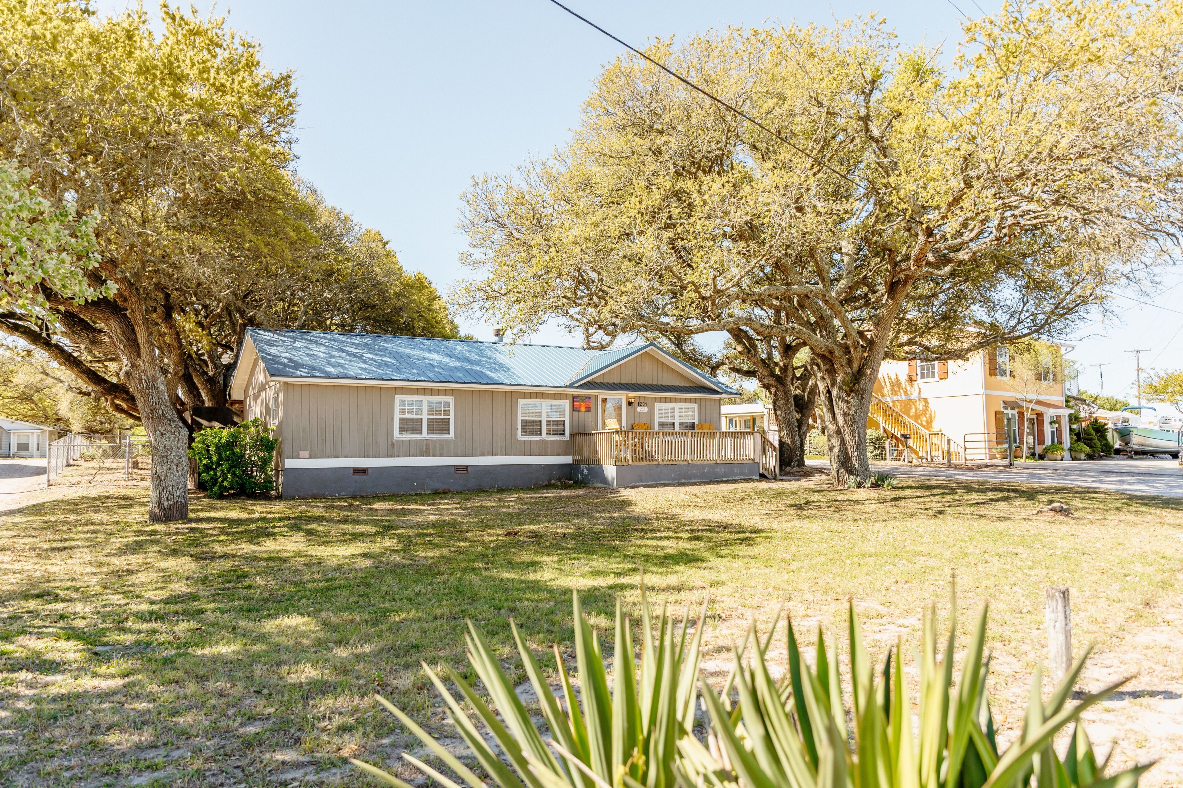 A single-story house with a sloped roof, a front porch, and a fenced yard.