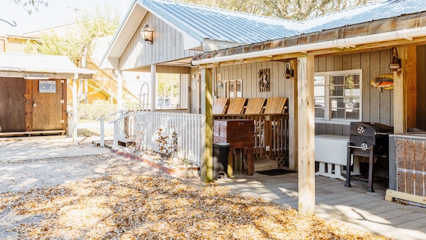 Een rustiek gebouw met een veranda, houten terras en een barbecuehoek.
