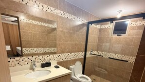 Een moderne badkamer met een dubbele wastafel, toilet en een douchecabine met glazen wanden.
