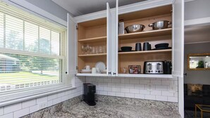 A kitchen with white cabinets, a granite countertop, and a window with blinds. - Comfortable 2BR for Longer Stays in The Plaza / Noda Area (Charlotte)