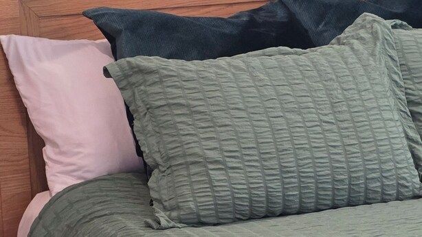 A bed with a green quilt, a dark green pillow, and a pink pillow. - pet friendly mid-century cottage near beaches (Fort Walton Beach)