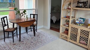 A dining area with a wooden table and chairs, a patterned rug, and a wicker console table with decorative items. - pet friendly mid-century cottage near beaches (Fort Walton Beach)