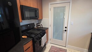 A kitchen with a black stove, a microwave, and wooden cabinets. - pet friendly mid-century cottage near beaches (Fort Walton Beach)