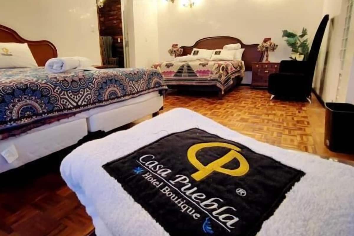 A hotel room with two beds, a wooden floor, and a wall decorated with string lights.