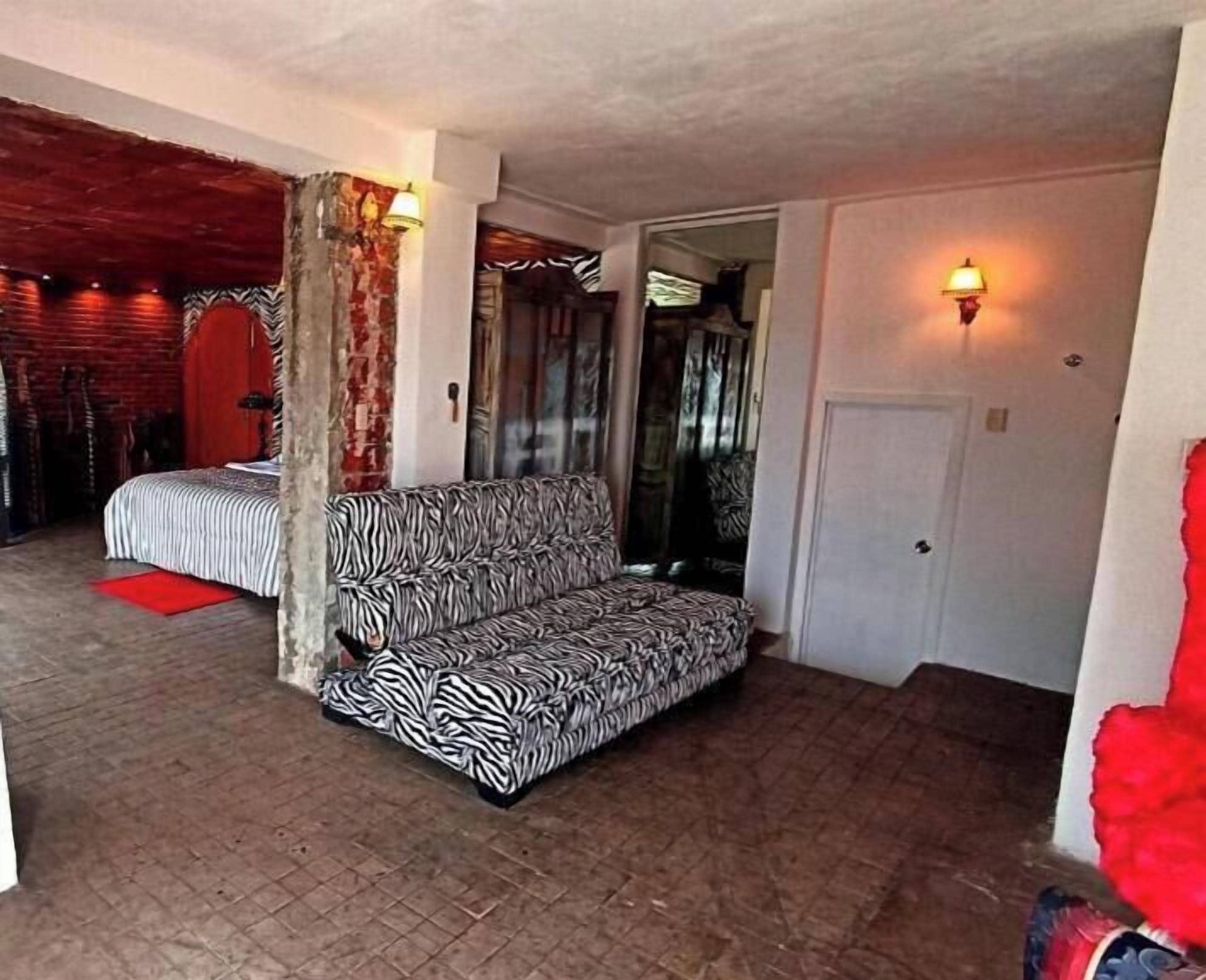 A room with a zebra-patterned sofa, a red rug, and a brick wall.