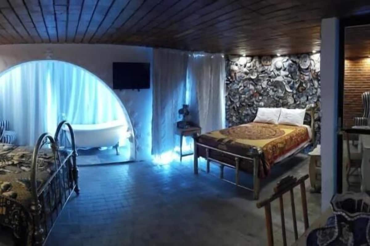A room with two beds, a stone wall, a brick wall, and a ceiling with wooden beams.