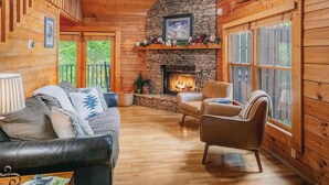 L’intérieur d’un chalet chaleureux, avec une cheminée en pierre, des murs en bois et un plancher en bois.