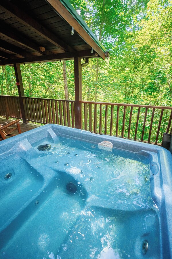 A hot tub on a wooden deck with a view of a forest. - Romantic Couple's Cabin 15 min to Pigeon Forge (Sevierville)