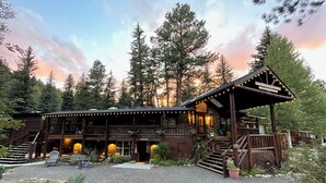 Eine Lodge mit Holzfassade, mehreren Etagen, Außenbestuhlung und einer Veranda.