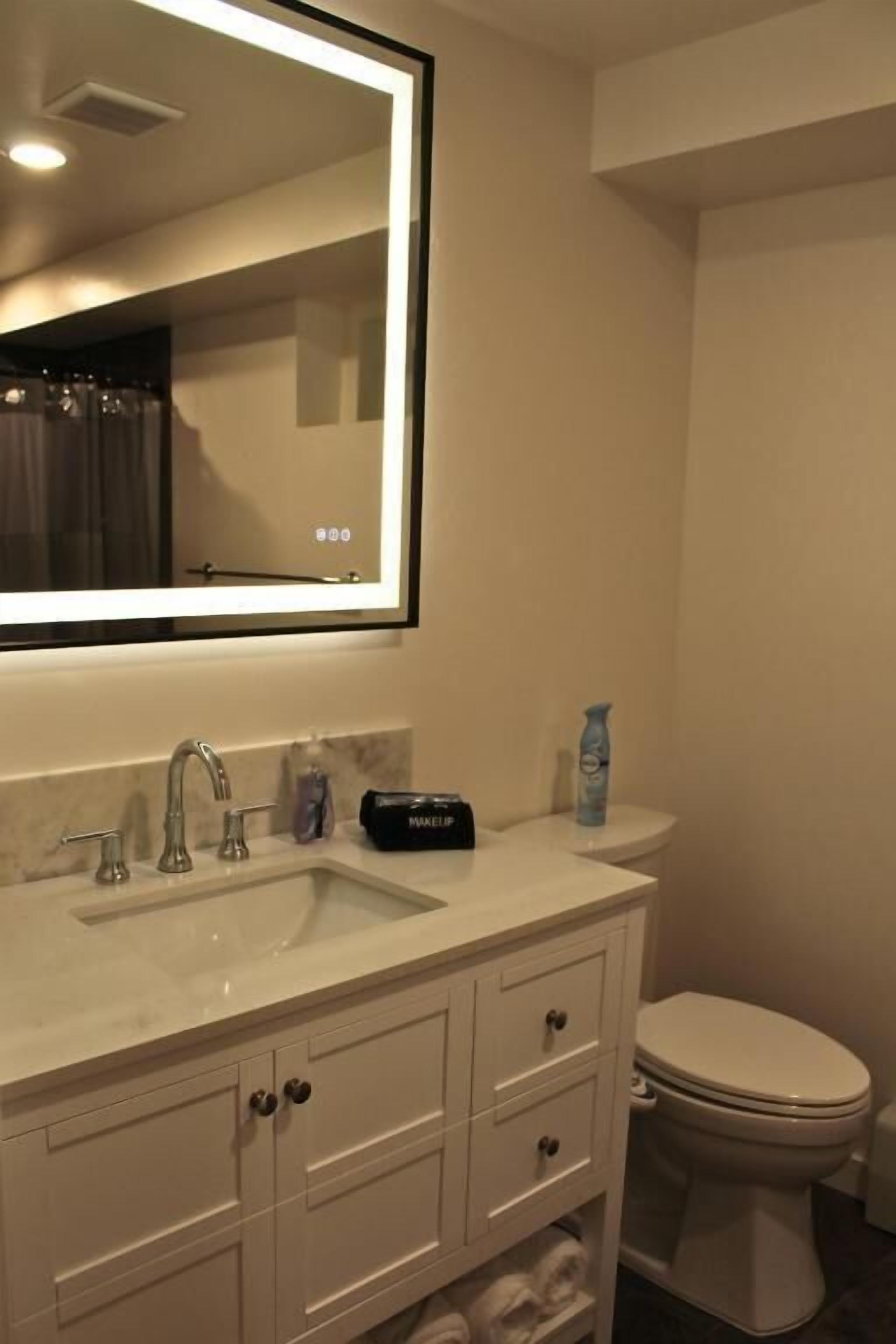 A bathroom with a white sink, a mirror, a toilet, and a towel rack.