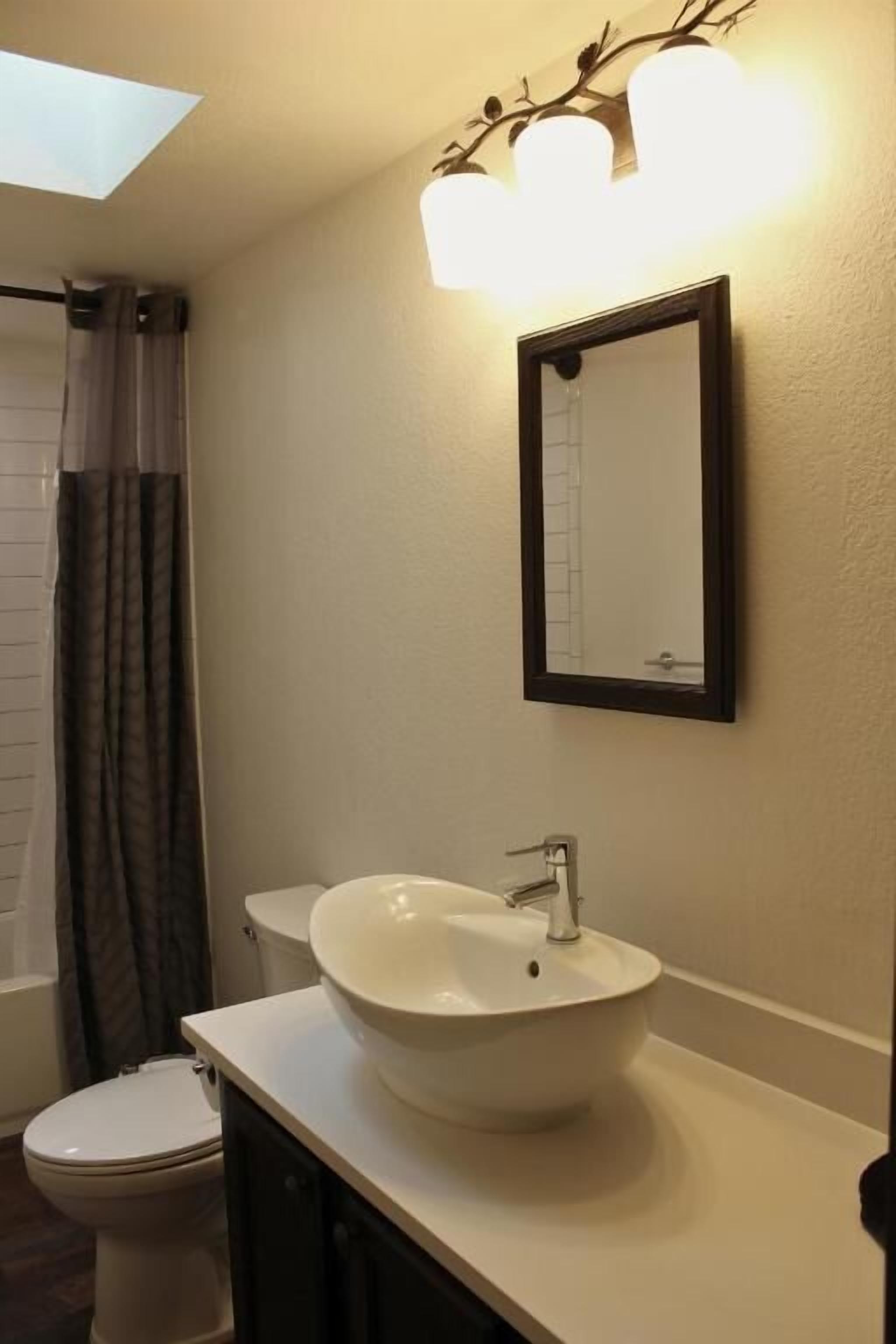 A bathroom with a white sink, a mirror, and a shower curtain.