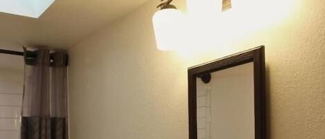 Et badeværelse med en hvid vask, et spejl og en bruseforhæng.