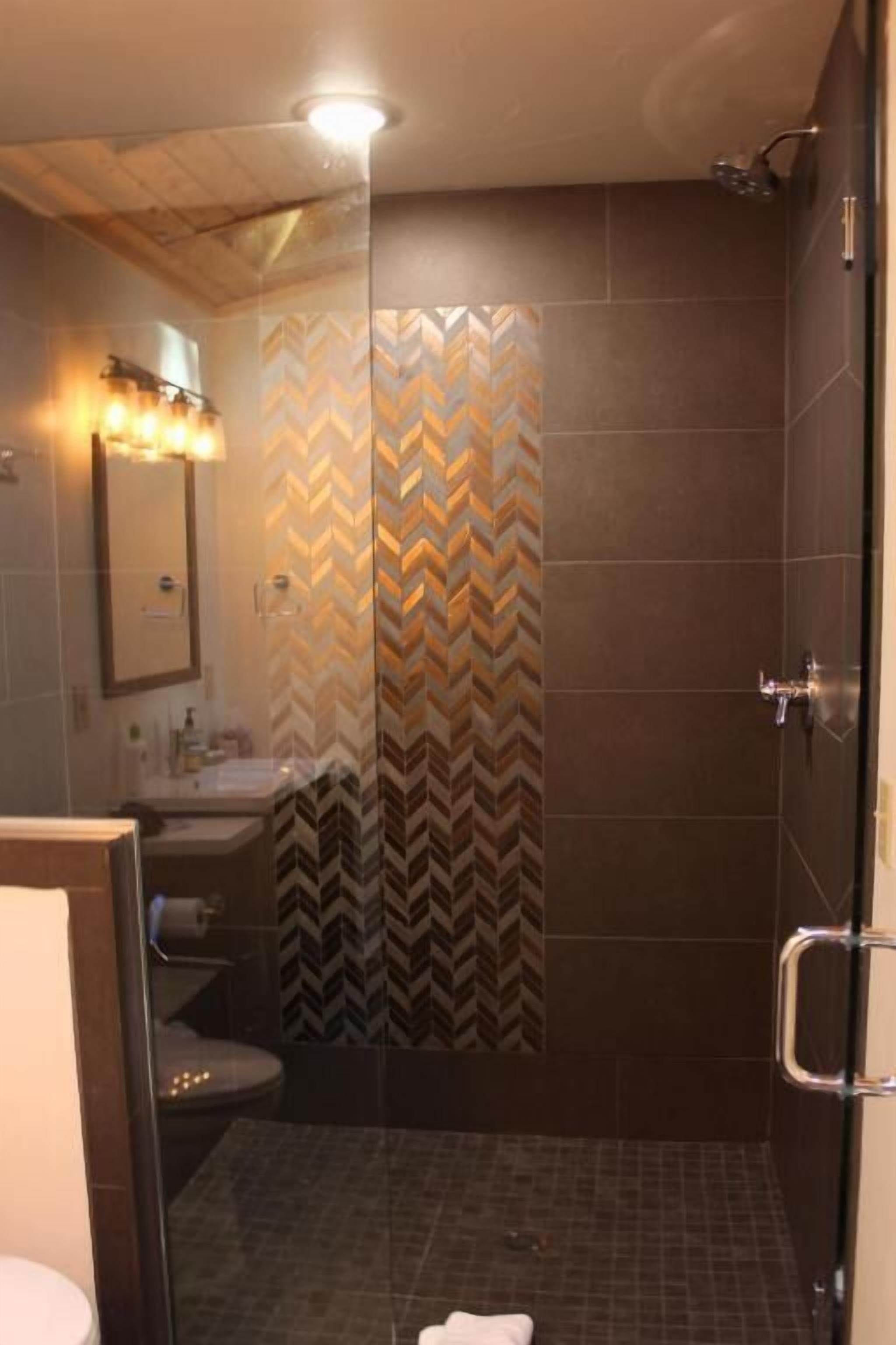 A modern bathroom with a shower, a toilet, and a sink.