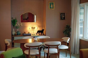A dining area with a brick wall, a mirror, and a cat statue. There are four chairs and a table. - Vino Villa | Cozy Escape near Wineries & Lake (Coloma)