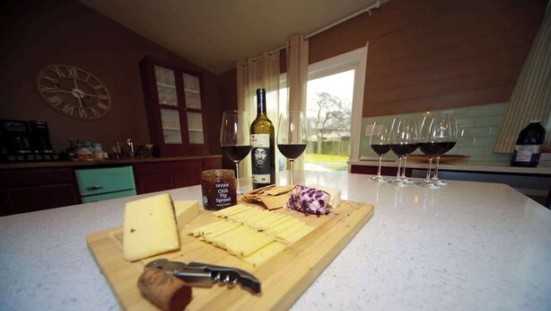 A kitchen counter with cheese, a bottle of wine, and glasses of wine. - Vino Villa | Cozy Escape near Wineries & Lake (Coloma)