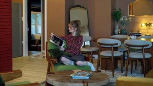 A person sitting on a green sofa in a room with a wooden floor, a mirror, and a table with chairs. - Vino Villa | Cozy Escape near Wineries & Lake (Coloma)