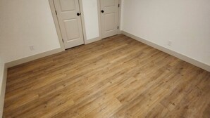 Ein Zimmer mit Holzboden, weißen Wänden und zwei geschlossenen Türen.