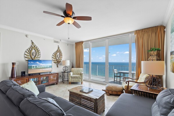 A modern living room with a sofa, a coffee table, a TV, and a ceiling fan. - San Carlos 1509 (Gulf Shores)