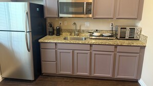 A kitchen with a stainless steel refrigerator, a microwave, a toaster, and a sink. - Charming 2-bedroom Rosena Casita with private 1-car garage and private entrance. (San Bernardino)