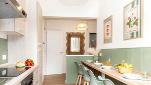 Una cocina moderna con comedor, que incluye una mesa de madera, sillas verdes y una isla de cocina con horno empotrado.