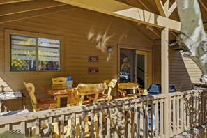 An outdoor wooden deck with wooden chairs and tables, a wooden fence, and a door leading to the interior. - Relaxing 3BR Cabin Close to Woodland Lake (Pinetop-Lakeside)