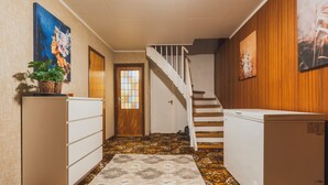 A hallway with patterned carpet, a wooden staircase, and a refrigerator. - Nordic Rest House NO PARKING CarFreeArea (Tromso)