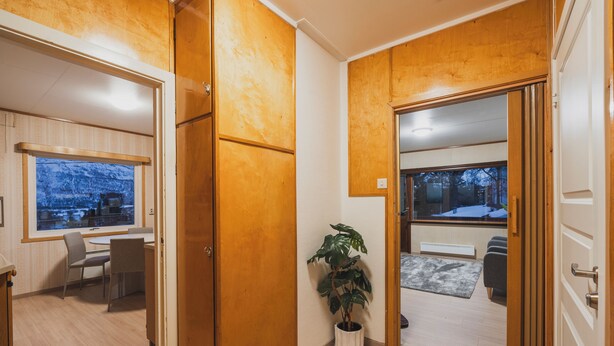 A modern interior with wooden paneling, a dining area with a table and chairs, a potted plant, and a view through a window. - Nordic Rest House NO PARKING CarFreeArea (Tromso)
