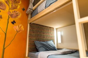 A bunk bed with a striped headboard, a window, and a wall with a floral painting and butterflies. - Stay With Hug Poshtel & Activities (Chiang Mai)
