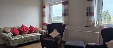 A living room with a sofa, two armchairs, and a small table.