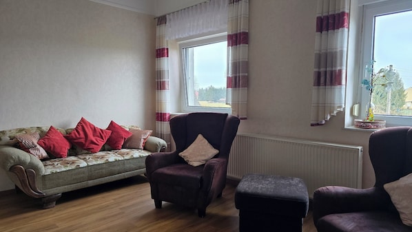 A living room with a sofa, two armchairs, and a small table.